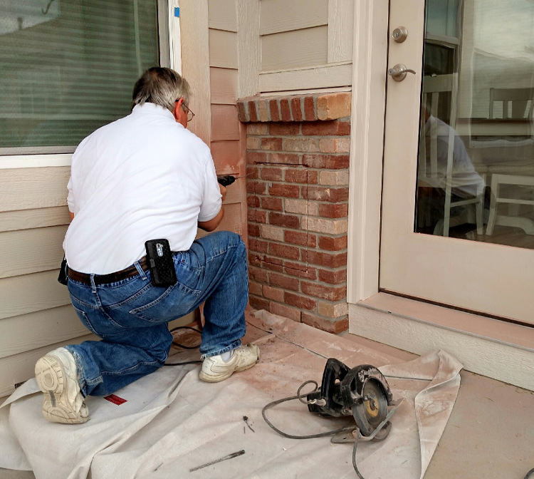 Owner Dan Tripp installing a dog door through brick